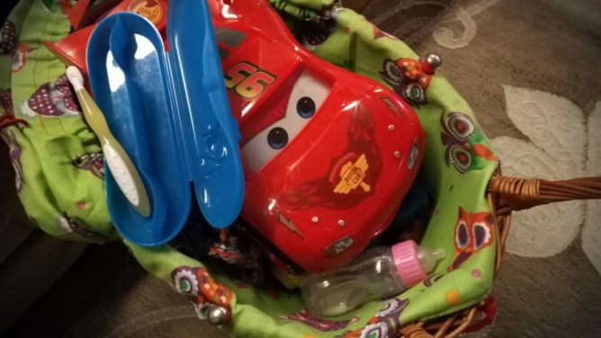 A racing car from Disney's Cars in a doll's pram.