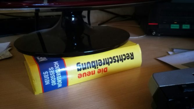 A dictionary under a computer monitor to increase the monitor height.